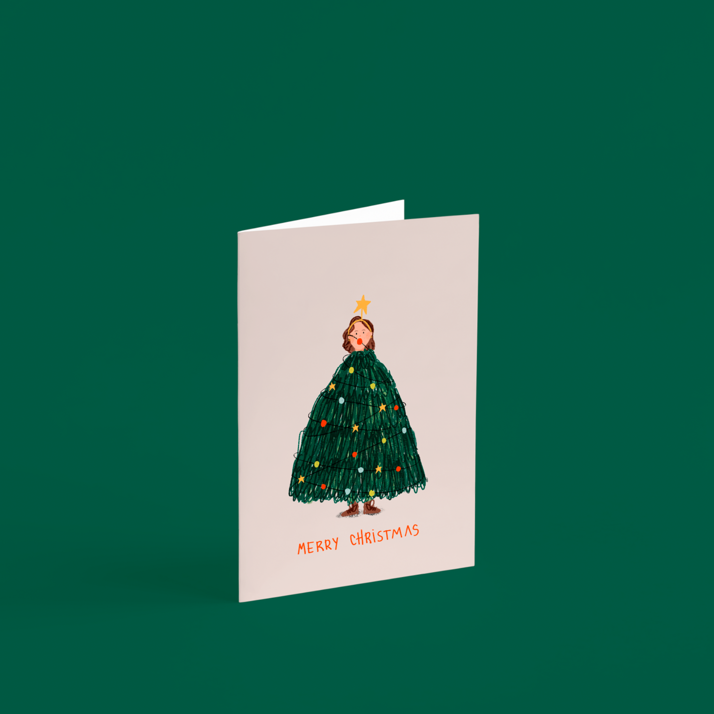 Tarjeta ilustrada “Merry Christmas” de Alejandra Lozano, con una mujer vestida de árbol de Navidad. Diseño artístico navideño con sobre kraft, estilo natural y tierno.