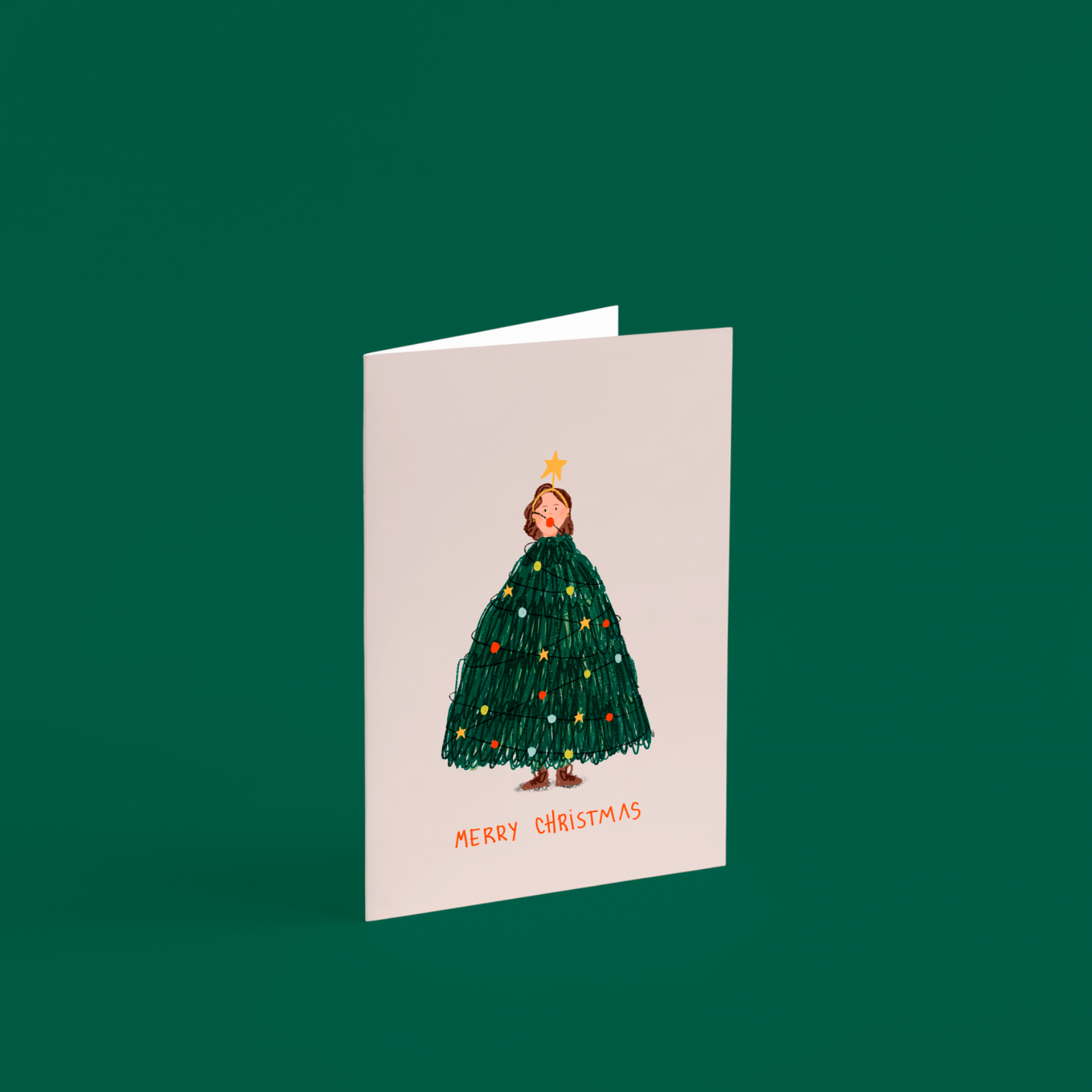 Tarjeta ilustrada “Merry Christmas” de Alejandra Lozano, con una mujer vestida de árbol de Navidad. Diseño artístico navideño con sobre kraft, estilo natural y tierno.